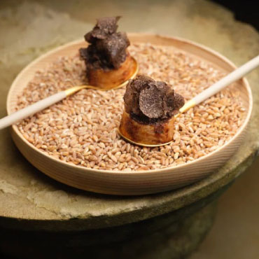 Two spoons on a plate of breadcrumbs topped with truffle